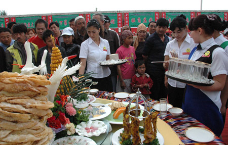 The waitresses place the table for food show at the International Tourism and Food Festival in Aksu city of northwest China's Xinjiang Uygur Autonomous Region, May 15, 2009. [Xinhua/Ma Yanfeng] 