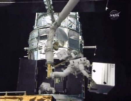 Astronaut Andrew Feustel, on the shuttle's robotic arm, moves the Corrective Optics Space Telescope Axial Replacement or COSTAR to a temporary storage location in the payload bay of Atlantis as fellow spacewalker John Grunsfeld works inside the Hubble Space Telescope in this image from NASA TV May 16, 2009. The spacewalkers are focused on the installation of the telescope's new Cosmic Origins Spectrograph which will replace COSTAR inside the telescope. (Xinhua/Reuters Photo)