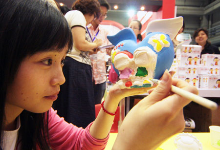 An exhibitor colors a ceramic toy in the three-day 11th Beijing International Toys and Preschool Tools Exhibition, opened in Beijing, capital of China, May 18, 2009. [Wu Changqing/Xinhua]