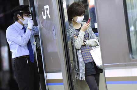 A railway conductor and a passenger wear facemasks at a station in Kobe, Hyogo prefecture, in western Japan, May 17, 2009. [Xinhua/AFP]