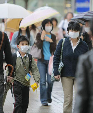 People wearing protective masks walk on a street in Kobe in western Japan on May 16, 2009. [Xinhua/AFP] 