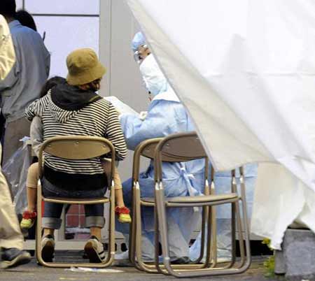 A parent and child undergo a check-up at a tent for fever outpatients in front of a hospital where high school students infected with new H1N1 influenza are hospitalized, in Kobe, western Japan, May 16, 2009. [Xinhua/Reuters]