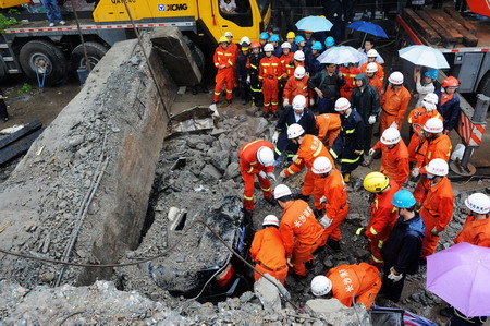 Rescuers examine the buried road at the site of a viaduct collapse accident that had killed 9 and injured 16 in downtown Zhuzhou, central China's Hunan province, Monday May 18, 2009. [Xinhua] 