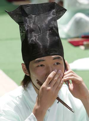 A man in traditional Korean costume uses his mobile phone after a ceremony celebrating the Coming-Of-Age Day at a university in Seoul May 18, 2009. The traditional Coming-Of-Age ceremony is a ceremony that endows boys and girls at the age of 20, who have lived under the protection of families, with individual authorities.[Xinhua/Reuters]