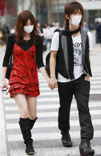 People wearing masks walk on a street in Tokyo, May 19, 2009. The latest statistics showed that the number of A/H1N1 influenza cases in Japan has risen to 178 after 15 more patients were confirmed on Tuesday. [Xinhua]