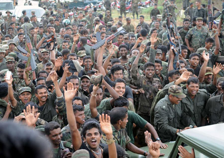 Sri Lankan soldiers celebrate after seeing the body of Liberation Tigers of Tamil Eelam (LTTE) leader Vellupillai Prabhakaran being carried on a stretcher at Nanthikadal lagoon, near the town of Mullaittivu in northern Sri Lanka May 19, 2009.[China Daily/Agencies]