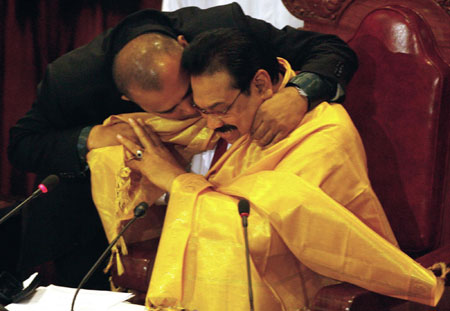 Sri Lankan President Mahinda Rajapaksa (R) has a garment put around him by Minister of Water Supply and Drainage A. L. M. Athaullah after addressing the nation in the parliament in Colombo May 19, 2009. Rajapaksa said the entire country was now under government control, saying 'We have totally liberated the country from Tamil Tiger terrorism. [China Daily/Agencies]