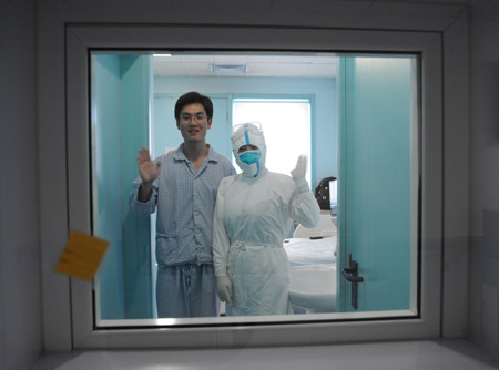 An isolated patient whose surname is Qin and a nurse wave to reporters at the isolation ward at the Beijing Ditan Hospital in Beijing, capital of China, May 20, 2009. [Li Wen/Xinhua]