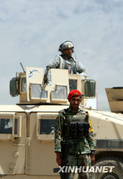 An Afghan national army soldier guards at the wreckage of a vehicle as a U.S. soldier standing in a armed vehicle after a blast on the way to Bagram, a U.S. airbase in north Kabul, capital of Afghanistan, May 20, 2009. [Zabi Tamanna/Xinhua]