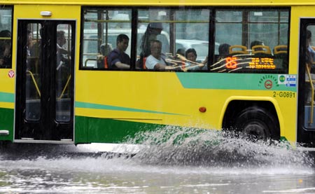 A bus runs in the rain in Guangzhou, capital of south China's Guangdong Province, May 20, 2009. A rainstorm hit Guangzhou Wednesday and affected drainage system and traffic. [Chen Yehua/Xinhua]