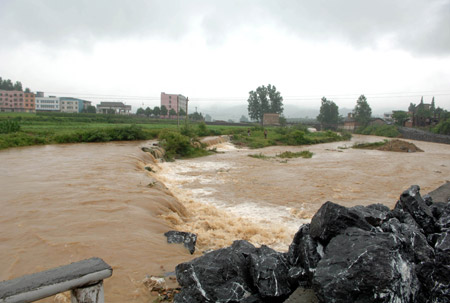 Flood water runs down the farmland near Chenzhou city, south China's Hunan province, May 20, 2009 after heavy rain swept across provinces in south China for the second day. [Li Xiwan/Xinhua]