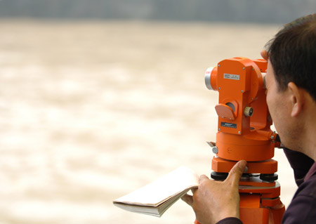 A local hydrologist staff observes the flood water level at a river in Chenzhou city, south China's Hunan province, May 20, 2009 after heavy rain swept across provinces in south China for the second day. [Li Xiwan/Xinhua]