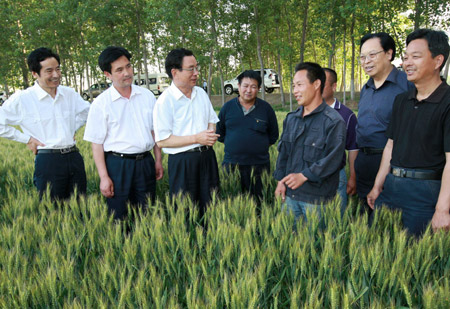 He Guoqiang (3rd L), secretary of the Communist Party of China (CPC) Central Commission for Discipline Inspection, also a memeber of the Standing Committee of the CPC Central Committee Political Bureau, inspects the wheat filed in Wangzhuang Village, Zhongmou County, Zhengzhou City, central China's Henan Province, May 18, 2009. He Guoqiang inspected several places in Henan Province from May 15 to 19.