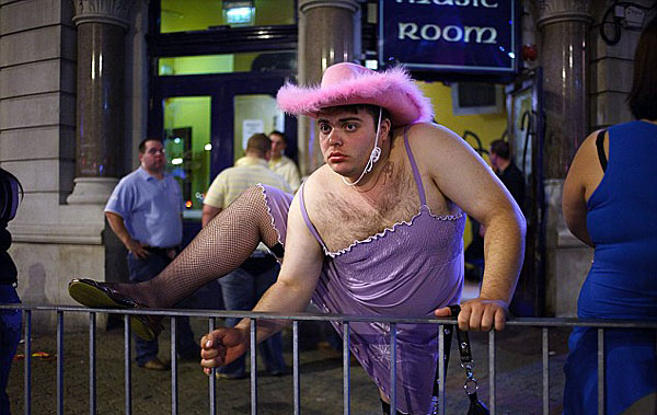 Pretty in pink: A reveller hikes up his skirt and hops over a barrier during a late night out [Chinanews.cn]