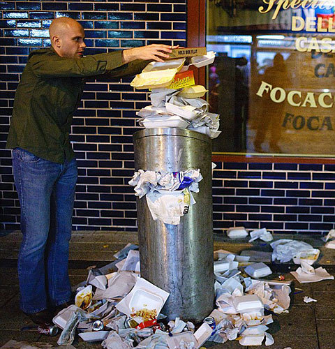  The leaning tower of rubbish: A man carefully balances a pizza box on top of an overflowing bin [Chinanews.cn]