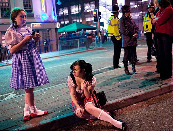 Not so innocent: Two girls dressed in Heidi-style outfits take a breather while the police look on [Chinanews.cn] 