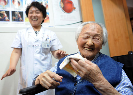 A 103-year-old senior female Li Chaolan enjoys her happiness with the nurse after having undergone a successful left eye's cataract operation and regained a normal eyesight, at the Gucheng Ophthalmological Hospital, in Xi'an, northwest China's Shaanxi Province, May 21, 2009.[Yuan Jingzhi/Xinhua] 