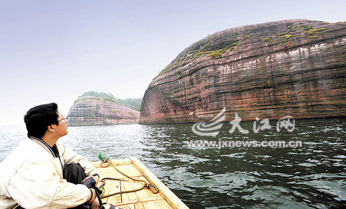 A tourist in boat watches in awe at the view of another Danxia-landformed mountain, which was recently discovered in a reservoir 20 kilometers away from Lichuan County, east China's Jiangxi Province, in this photo taken Thursday, May 21, 2009.