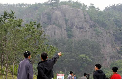 A man points to a mountain where former South Korean president Roh Moo-Hyun jumped off, near Roh's private residence at Bongha village in Gimhae, about 450 km southeast of Seoul on May 23, 2009. Former South Korean President Roh Moo-Hyun, who was at the centre of a multi-million dollar corruption probe, plunged to his death off a mountainside on May 23 in an apparent suicide. 