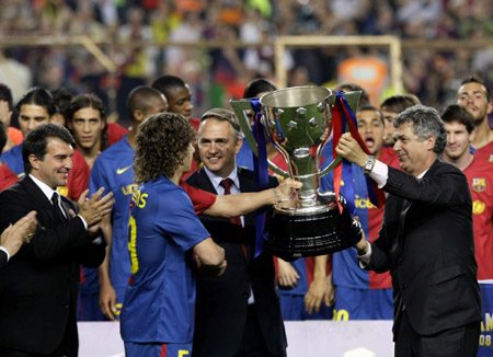 Spanish First Division President Angel Maria Villar (R) presents the championship trophy to Barcelona's captain Carles Puyol as Barcelona's president Joan Laporta (L) applauds at Nou Camp stadium in Barcelona May 23, 2009.(Xinhua/Reuters Photo)