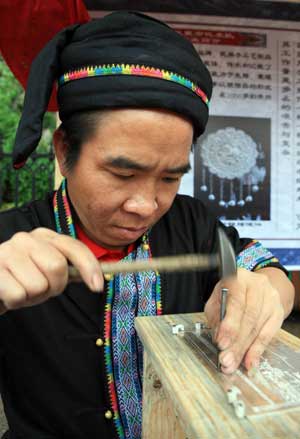 A Chinese craftsman of Miao ethinc minority showcases how to make traditional silver ornament at a gathering in Fenghuang county, central south China's Hunan province, May 23, 2009. The gathering is aimed to promote the culture of China's Miao ethnic minority, especially their tradition of wearing different designs of silver ornament. (Xinhua/Long Tao) 