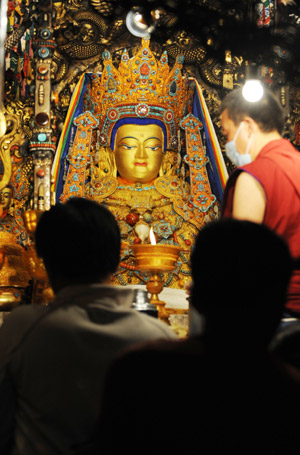 People pray in front of a figure of buddha in the Jokhang Temple in Lhasa, southwest China's Tibet Autonomous Region, while celebrating the Sakadawa Festival, May 25, 2009. The Sakadawa Festival, which begins on the First Day of the Fourth Month of the Tibetan Calendar and lasts one month, is celebrated by Tibetan Buddhists to commemorate the Buddha's birth, enlightenment and death. (Xinhua/Gesang Dawa)