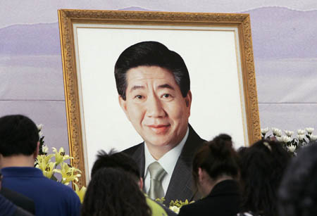 A portrait of deceased former President Roh Moo-hyun is seen as people mourn during a memorial service at Roh's hometown Bonghwa village in Gimhae, about 450 km (280 miles) southeast of Seoul, May 25, 2009.