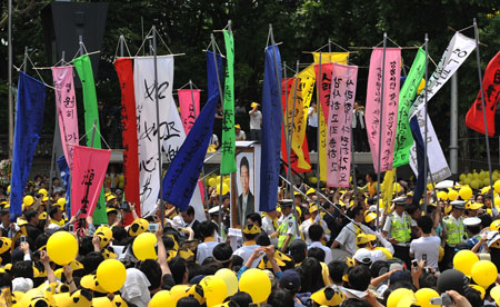 Mourners wearing yellow hats, Roh Moo-hyun's symbol color as it was used for his 2002 presidential election, wait for the late president's hearse on a street in central Seoul, capital of South Korea, on May 29, 2009. The funeral of Roh was held Friday in Seoul's historic royal palace, Gyeongbok Palace, attended by some 3,000 people, including President Lee Myung-bak. 