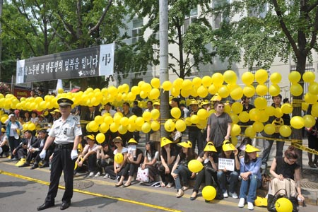 Mourners hold yellow ribbons, Roh Moo-hyun's symbol color as it was used for his 2002 presidential election, as they wait for the late president's hearse on a street in central Seoul, capital of South Korea, on May 29, 2009. 