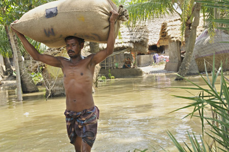 A man carries a sack of rice as he wades through the floodwaters in Khulna, southwestern Bangladesh, on May 28, 2009. 