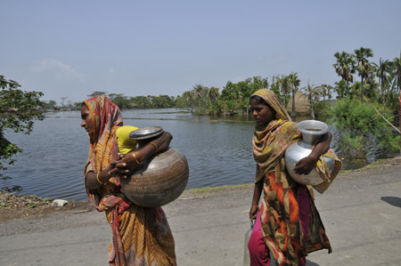 Women carry pots of drinking water that they fetch from a distant place, in Khulna, southwestern Bangladesh, on May 28, 2009. 