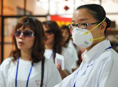 A quarantine official (R) guides passengers for temperature examination at the Maweigang dock in Fuzhou, capital of southeast China's Fujian Province, May 30, 2009. The third case of A/H1N1 in Fujian was confirmed in Fuzhou on May 29. (Xinhua/Zhang Guojun)