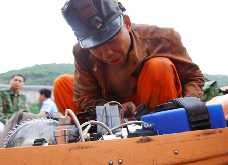 A rescuer checks his equipment at the entrance to a coal mine where a colliery gas burst at Tonghua Coal Mine in southwest China's Chongqing Municipality, on May 30, 2009. The accident has killed 30 and injured 59 miners.