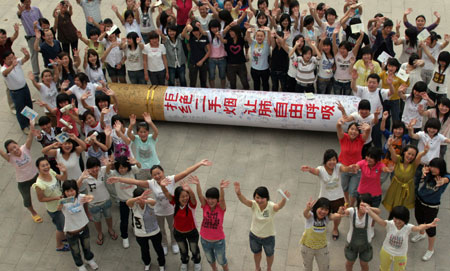 Students with the Huaibei Health School gesticulate around a 5-meter-long gigantic cigarette, a hand-made model for a smoking-deserting publicity on the World No Tobacco Day which falls on May 31, on their campus in Huaibei, east China's Anhui Province, May 30, 2009. (Xinhua/Li Bo) 