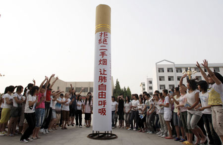 Students with the Huaibei Health School gesticulate around a 5-meter-long gigantic cigarette, a hand-made model for a smoking-deserting publicity on the World No Tobacco Day which falls on May 31, on their campus in Huaibei, east China's Anhui Province, May 30, 2009. (Xinhua/Li Bo)