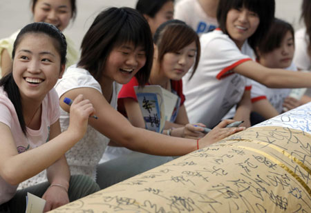 Students with the Huaibei Health School put respective signatures on a 5-meter-long gigantic cigarette, a hand-made model for a smoking-deserting publicity on the World No Tobacco Day which falls on May 31, on their campus in Huaibei, east China's Anhui Province, May 30, 2009. (Xinhua/Li Bo)