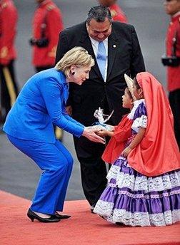 US Secretary of State Hillary Clinton (L) receives a gift from Salvadorean children in traditional dress upon her arrival at El Salvador International Airport in Comalapa, some 45 kilometers south of San Salvador. Clinton began a visit to Central America Sunday, amid new US steps toward ties with Cuba that Washington hopes will slow a sudden regional push to end Havana's isolation. [Yuri Cortez/AFP] 
