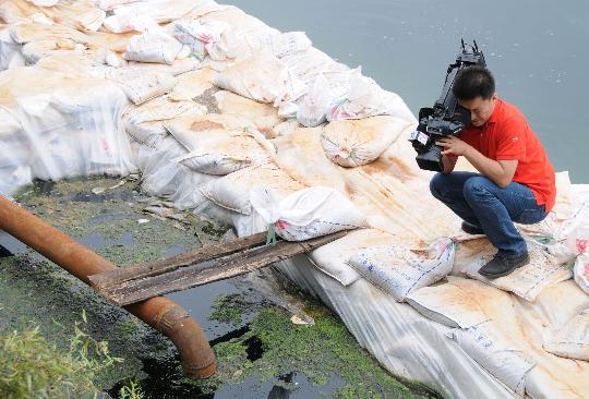 A reporter takes photos of the polluted Yangzonghai Lake, which covers 186 square kilometers and flows through the counties of Chengjiang, Chenggong and Yiliang in Yunnan, on September 20, 2009. [Xinhua photo]