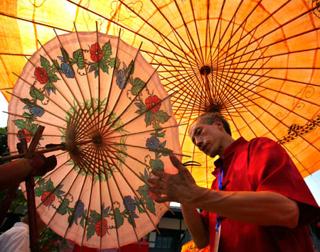 Zhou Degui, an umbrella maker, shows antique Fenshui oil paper umbrella making skills during the 2nd International Festival of the Intangible Cultural Heritage in Chengdu, capital of southwest China&apos;s Sichuan Province, June 2, 2009. The Fenshui oil paper umbrella has a history of 400 years.(Xinhua/Zeng Shuo)