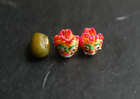 Photo taken on June 3, 2009 shows the handmade mini shoes craftwork made by Ren Tingli comparing to a mung bean in Chifeng city in north China's Inner Mongolia Autonomous Region, June 3, 2009. [Photo: Xinhua] 