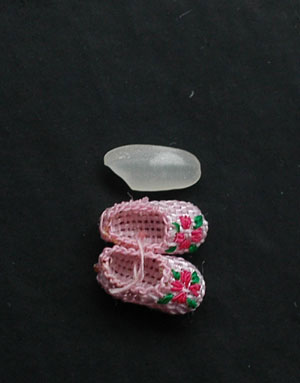 Photo taken on June 3, 2009 shows the handmade mini shoes craftwork made by Ren Tingli comparing to rice in Chifeng city in north China&apos;s Inner Mongolia Autonomous Region, June 3, 2009. [Photo: Xinhua]