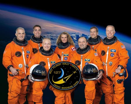 Attired in training versions of their shuttle launch and entry suits, the STS-127 crew pose in this October 10, 2008 NASA image. On the front row are Commander Mark Polansky (R) and Pilot Doug Hurley. The remaining crew members are (L-R) astronauts Dave Wolf, Christopher Cassidy, Canadian Space Agency's Julie Payette, Tom Marshburn and Tim Kopra, all mission specialists. Kopra is scheduled to join Expedition 20 as flight engineer after launching to the International Space Station with the STS-127 crew. 