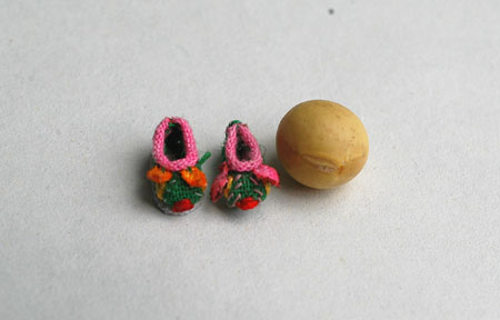 Photo taken on June 3, 2009 shows the handmade mini shoes craftwork made by Ren Tingli comparing to a soybean in Chifeng city in north China's Inner Mongolia Autonomous Region, June 3, 2009.