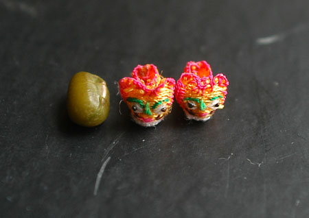 Photo taken on June 3, 2009 shows the handmade mini shoes craftwork made by Ren Tingli comparing to a mung bean in Chifeng city in north China's Inner Mongolia Autonomous Region, June 3, 2009.