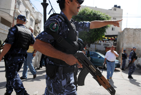 A Palestinian policeman dispels residents near the scene of the gunbattle in the northern West Bank city of Qalqilya June 4, 2009. (Xinhua/Yin Bogu)