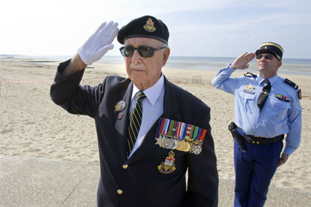 Canadian veteran of the Normandy D-Day invasion Harry Quarton (L) of Summerland, B.C. stands at attention near a French Gendarme police officer, as national anthems are played during a ceremony on 