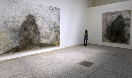 A visitor views paintings of gorillas entitled "La Solitude Organisative" (L) and "Flecha Rota" (R) by Spanish artist Miquel Barcelo of at the pavilion of Spain during the vernissage of the 53rd Biennale Internazional Art Exhibition in Venice June 5, 2009.
