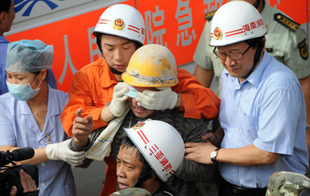 A worker (C) who was trapped in the collapsed tunnel is helped walk out after he is rescued in the Yingbin expressway tunnel near Sanya City in south China's Hainan Province, June 7, 2009. Eight workers who were trapped when a tunnel collapsed Thursday in south China's Hainan Province were rescued after 64 hours on Sunday afternoon.[Guo Cheng/Xinhua]