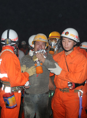 A worker who was trapped in the collapsed tunnel is helped walk out after he is rescued in the Yingbin expressway tunnel near Sanya City in south China's Hainan Province, June 7, 2009. Eight workers who were trapped when a tunnel collapsed Thursday in south China's Hainan Province were rescued after 64 hours on Sunday afternoon. [Hu Jianbing/Xinhua]