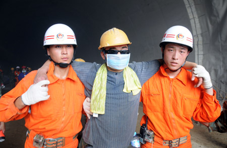 A worker who was trapped in the collapsed tunnel is helped walk out after he is rescued in the Yingbin expressway tunnel near Sanya City in south China's Hainan Province, June 7, 2009. Eight workers who were trapped when a tunnel collapsed Thursday in south China's Hainan Province were rescued after 64 hours on Sunday afternoon. [Hu Jianbing/Xinhua]